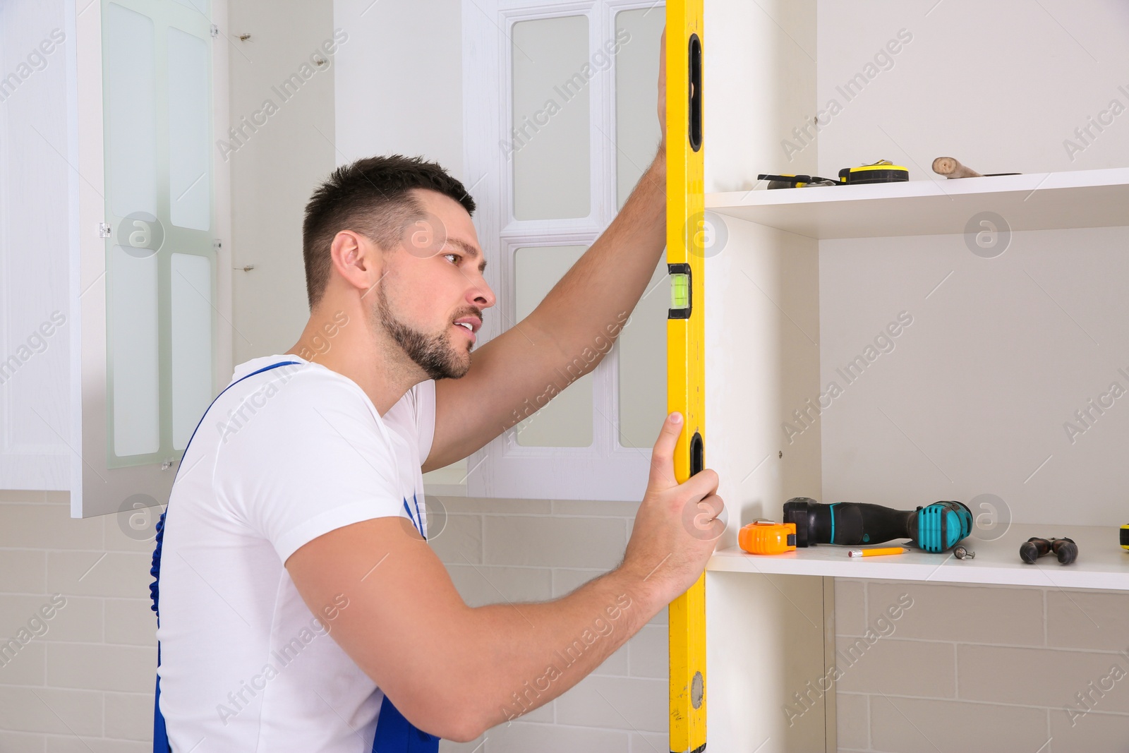 Photo of Worker measuring newly installed kitchen furniture indoors