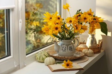 Photo of Composition with beautiful flowers, pumpkins and book on windowsill. Autumn atmosphere