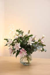 Photo of Bouquet of beautiful lily flowers in vase on wooden table against beige background