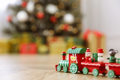 Bright toy train on floor in room with Christmas tree