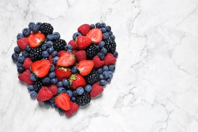 Photo of Heart made of different fresh ripe berries on white marble table, top view. Space for text
