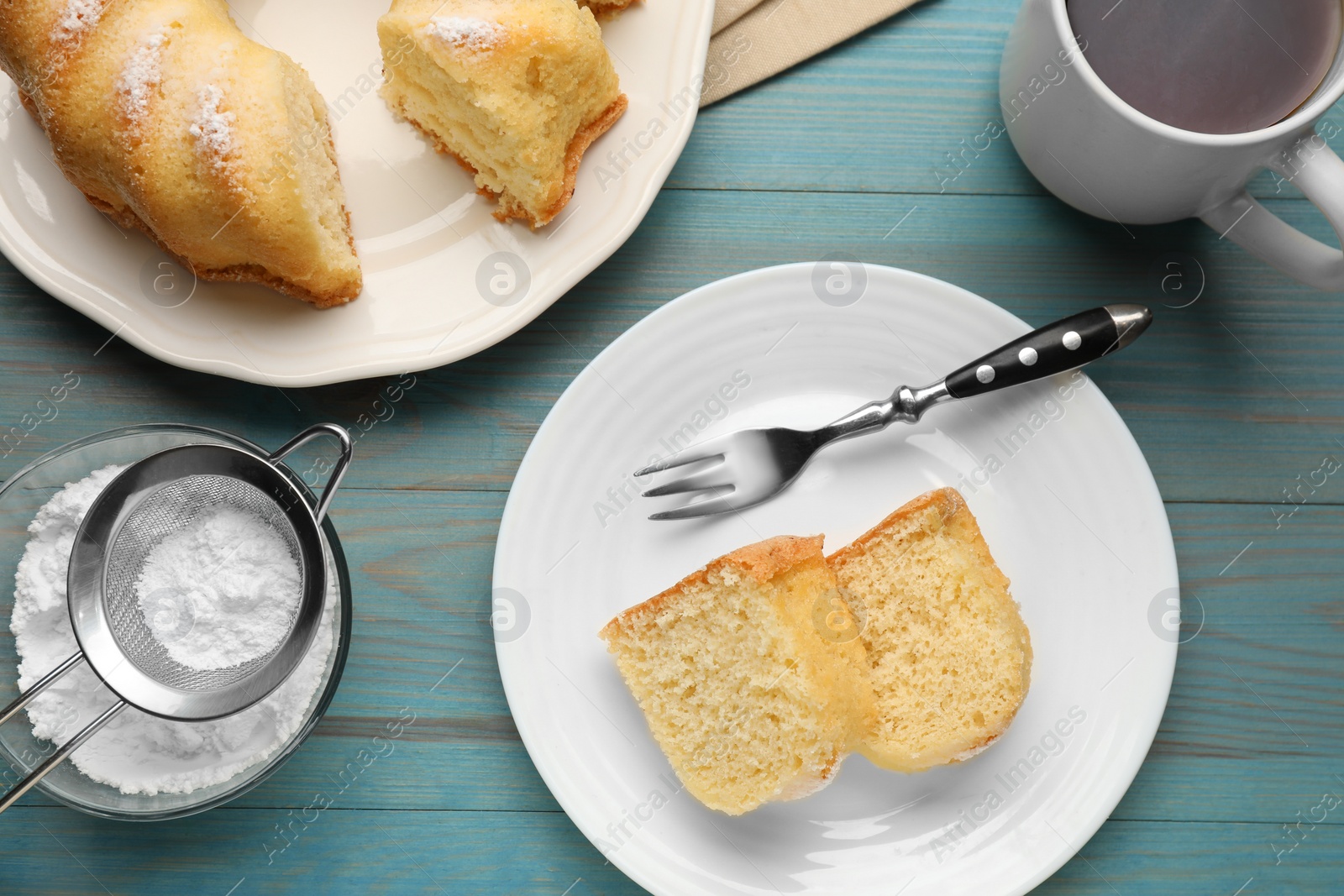 Photo of Delicious sponge cake served on light blue wooden table, flat lay