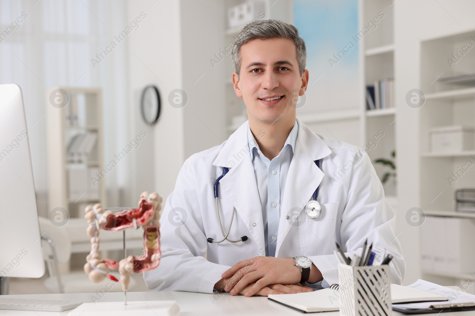 Photo of Gastroenterologist with anatomical model of large intestine at table in clinic