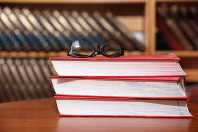 Photo of Stack of books and glasses on table in library