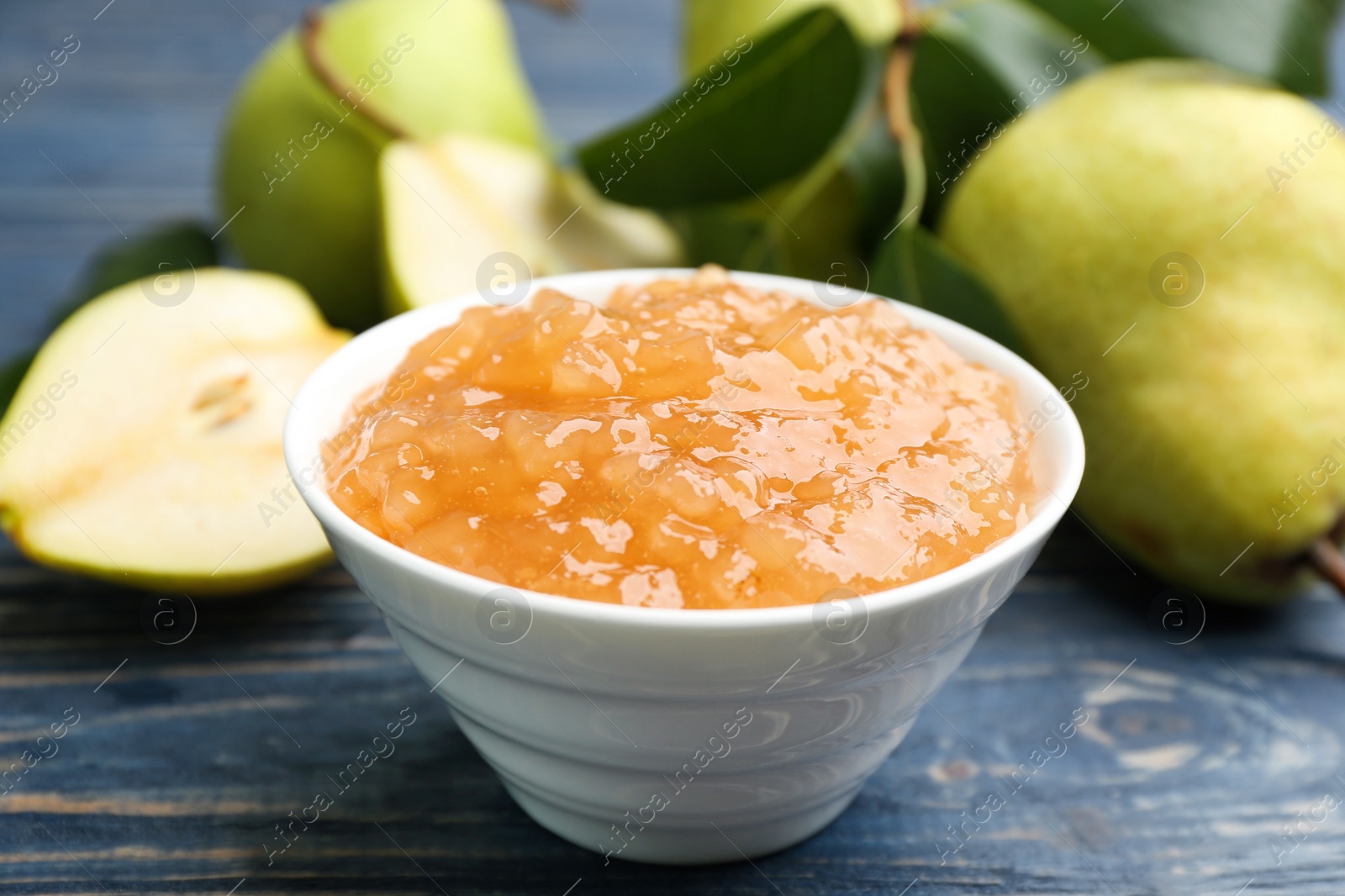 Photo of Tasty homemade pear jam and fresh fruits on blue wooden table