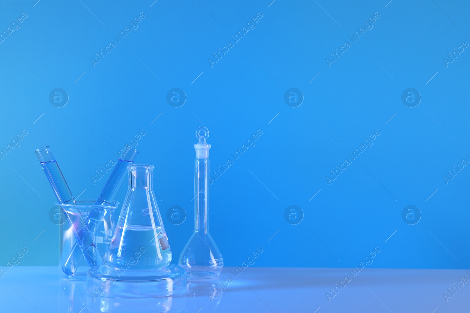 Photo of Laboratory analysis. Different glassware on table against light blue background