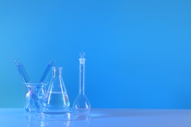 Photo of Laboratory analysis. Different glassware on table against light blue background