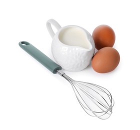 Photo of Whisk, raw eggs and jug of milk isolated on white, above view