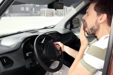 Photo of Sleepy man yawning while driving his car