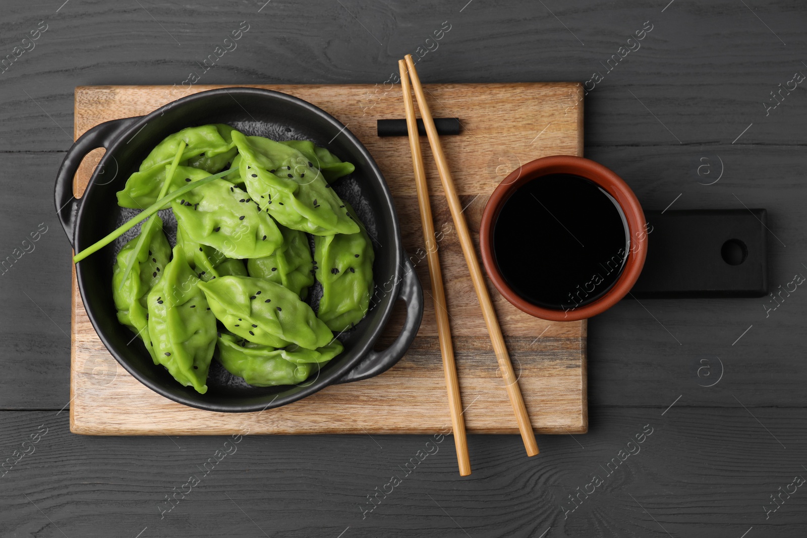 Photo of Delicious green dumplings (gyozas) served on grey wooden table, top view