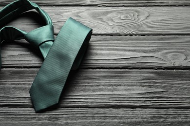 Photo of One green necktie on black wooden table, above view. Space for text