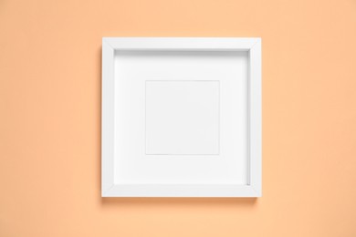 Photo of Empty photo frame on pale orange background, top view. Space for design