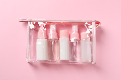 Photo of Cosmetic travel kit in plastic bag on pink background, top view. Bath accessories