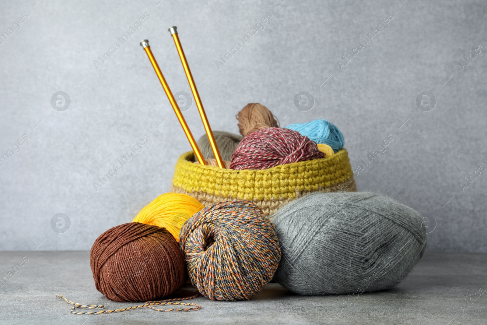 Photo of Soft woolen yarns and knitting needles on grey table