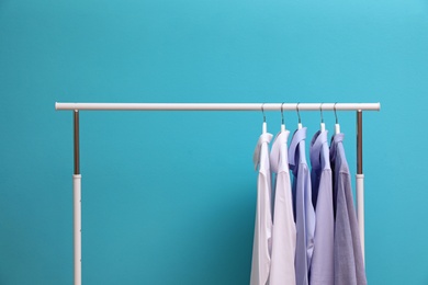Photo of Wardrobe rack with men's clothes on color background. Space for text
