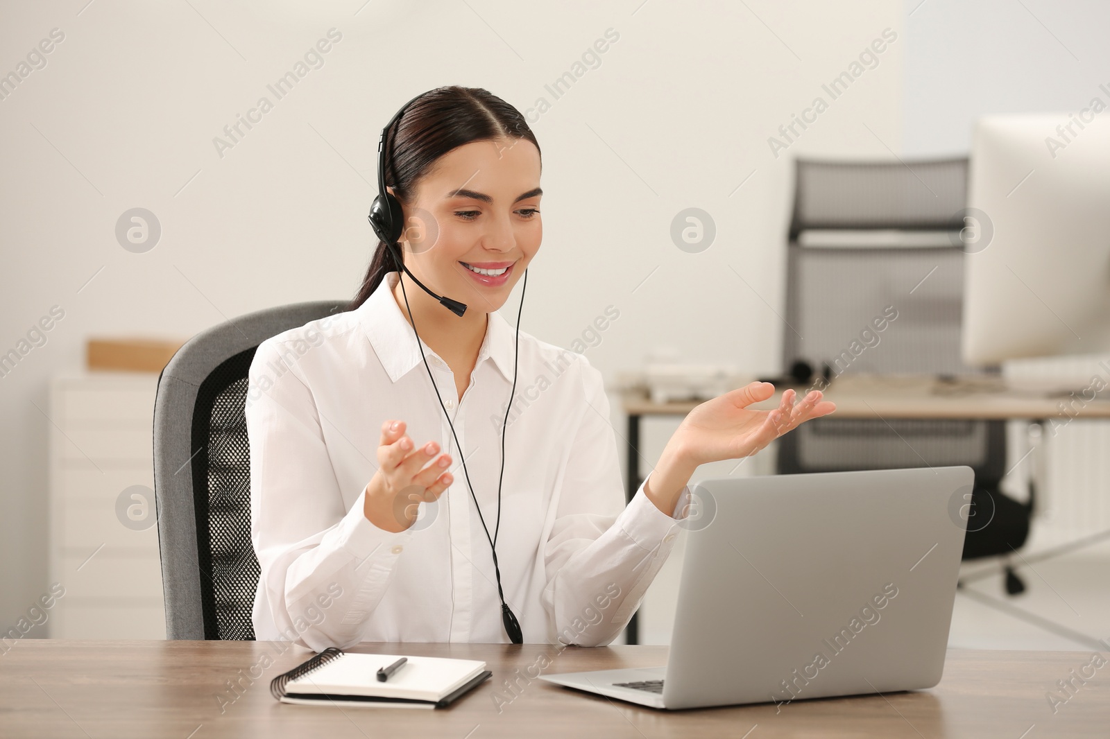 Photo of Hotline operator with headset working on laptop in office