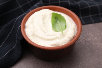 Photo of Delicious tofu sauce and basil leaf in bowl on brown table, closeup