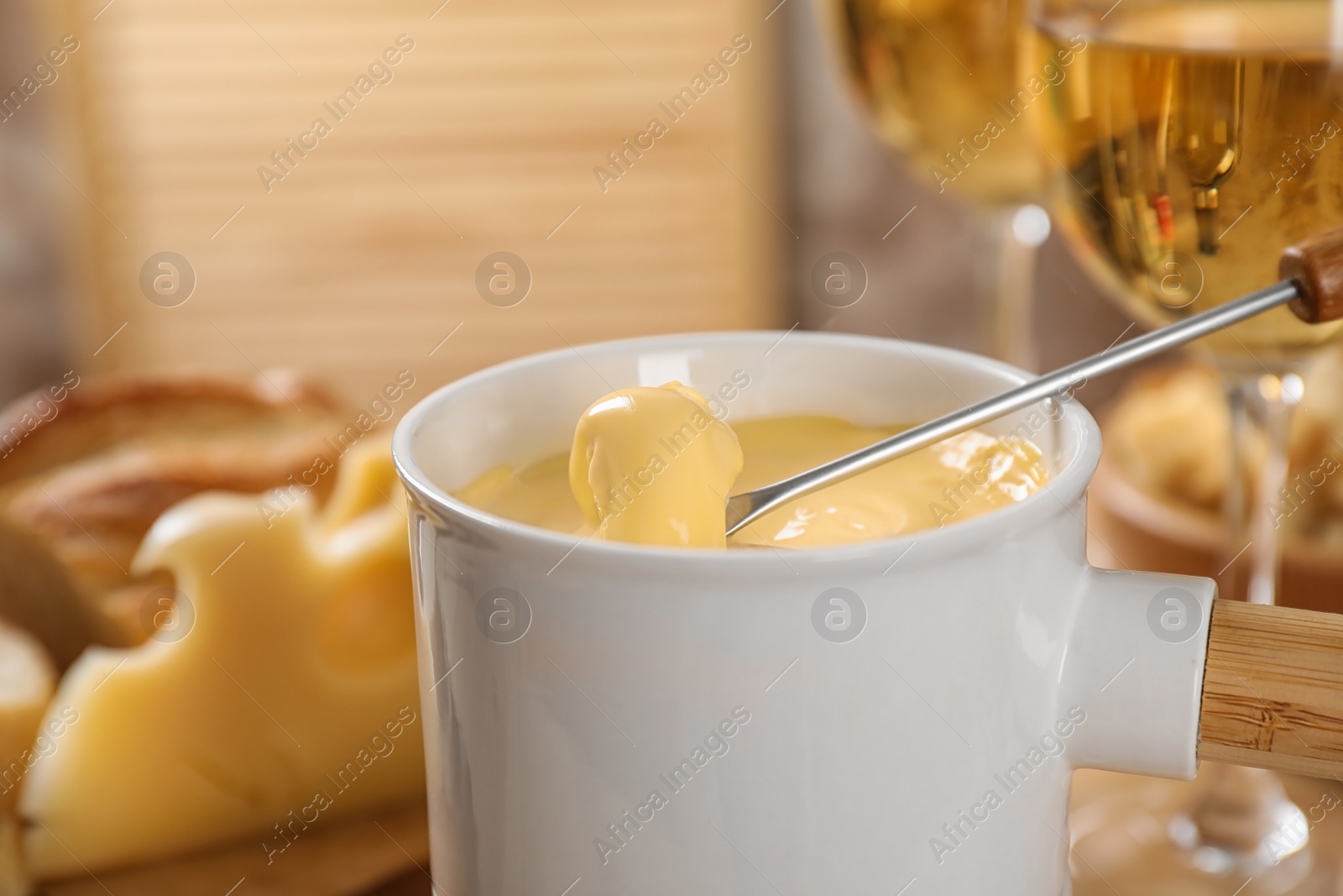 Photo of Pot of tasty cheese fondue and fork with bread on table