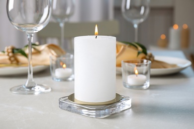 Photo of White burning wax candle on light table