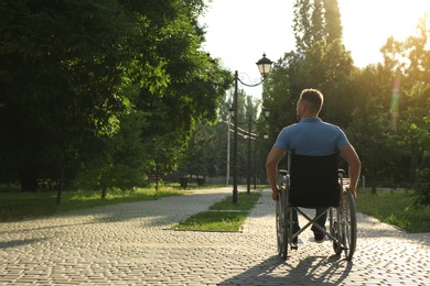 Photo of Man in wheelchair at park on sunny day. Space for text