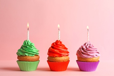 Photo of Delicious birthday cupcakes with candles on color background