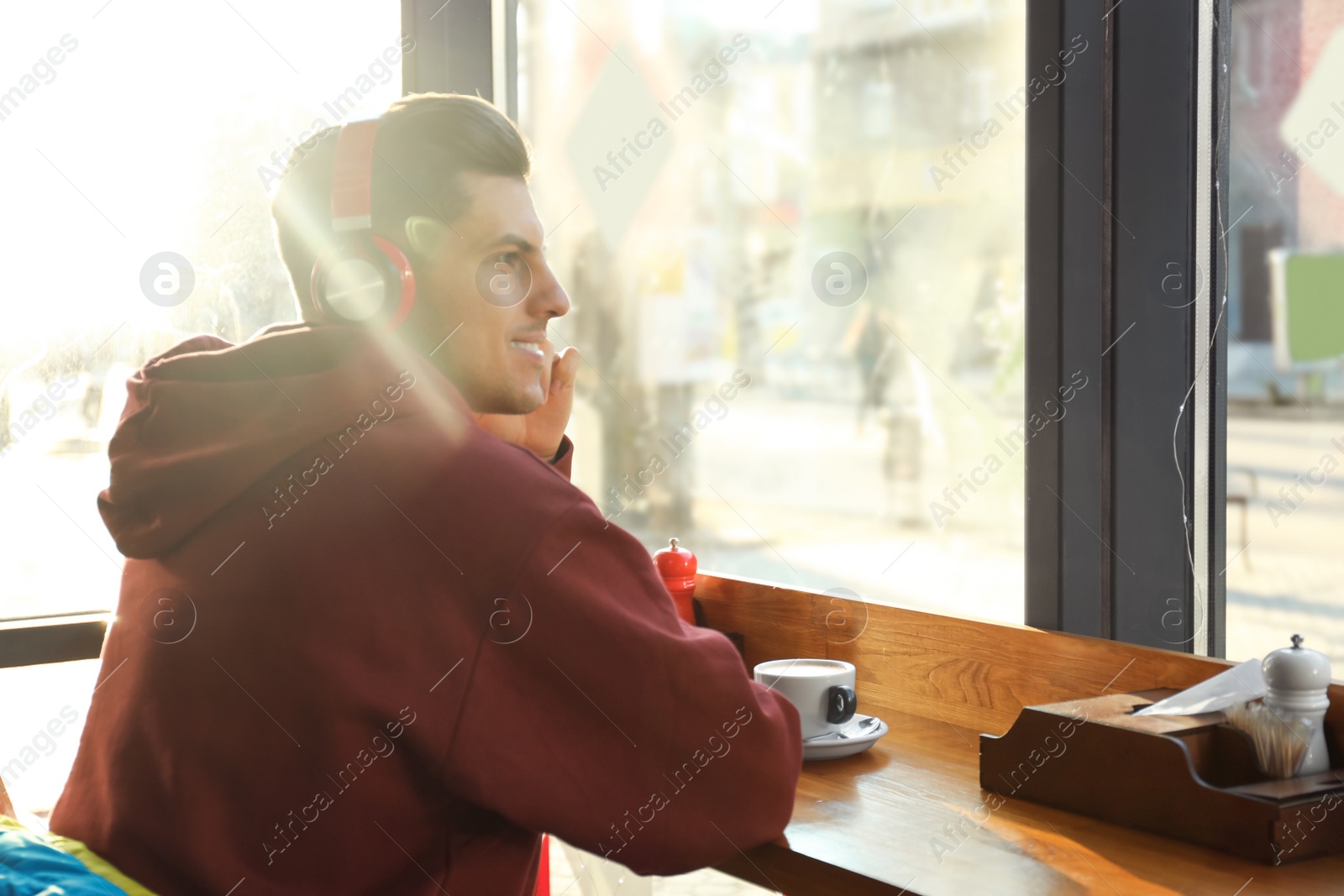 Photo of Man listening to audiobook at table in cafe