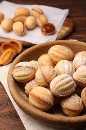 Delicious nut shaped cookies with boiled condensed milk and powdered sugar on wooden table, closeup