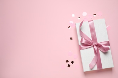 Photo of Beautiful gift box and confetti on pink background, flat lay. Space for text