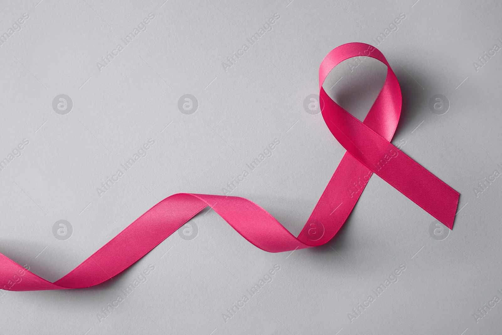 Photo of Pink ribbon on light grey background, top view. Breast cancer awareness concept