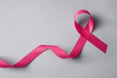 Pink ribbon on light grey background, top view. Breast cancer awareness concept