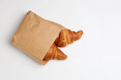 Photo of Paper bag with croissants on white background, top view. Space for design