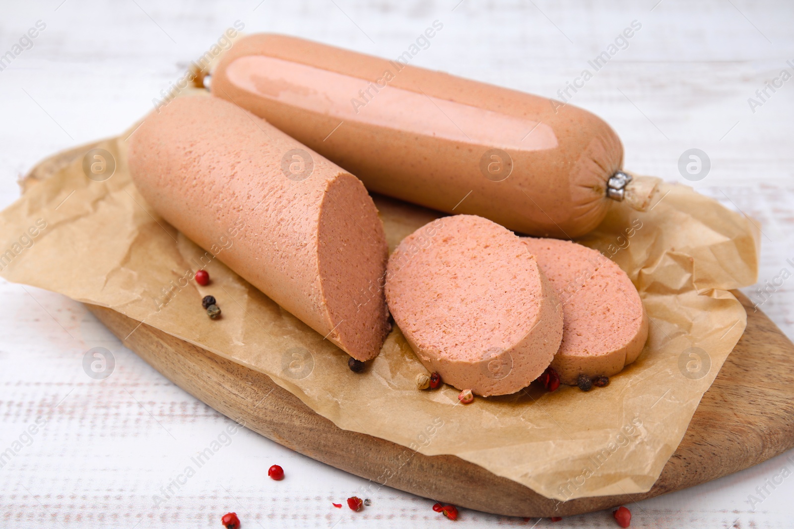 Photo of Board with delicious liver sausage on white wooden table, closeup