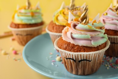 Cute sweet unicorn cupcakes on yellow background, closeup