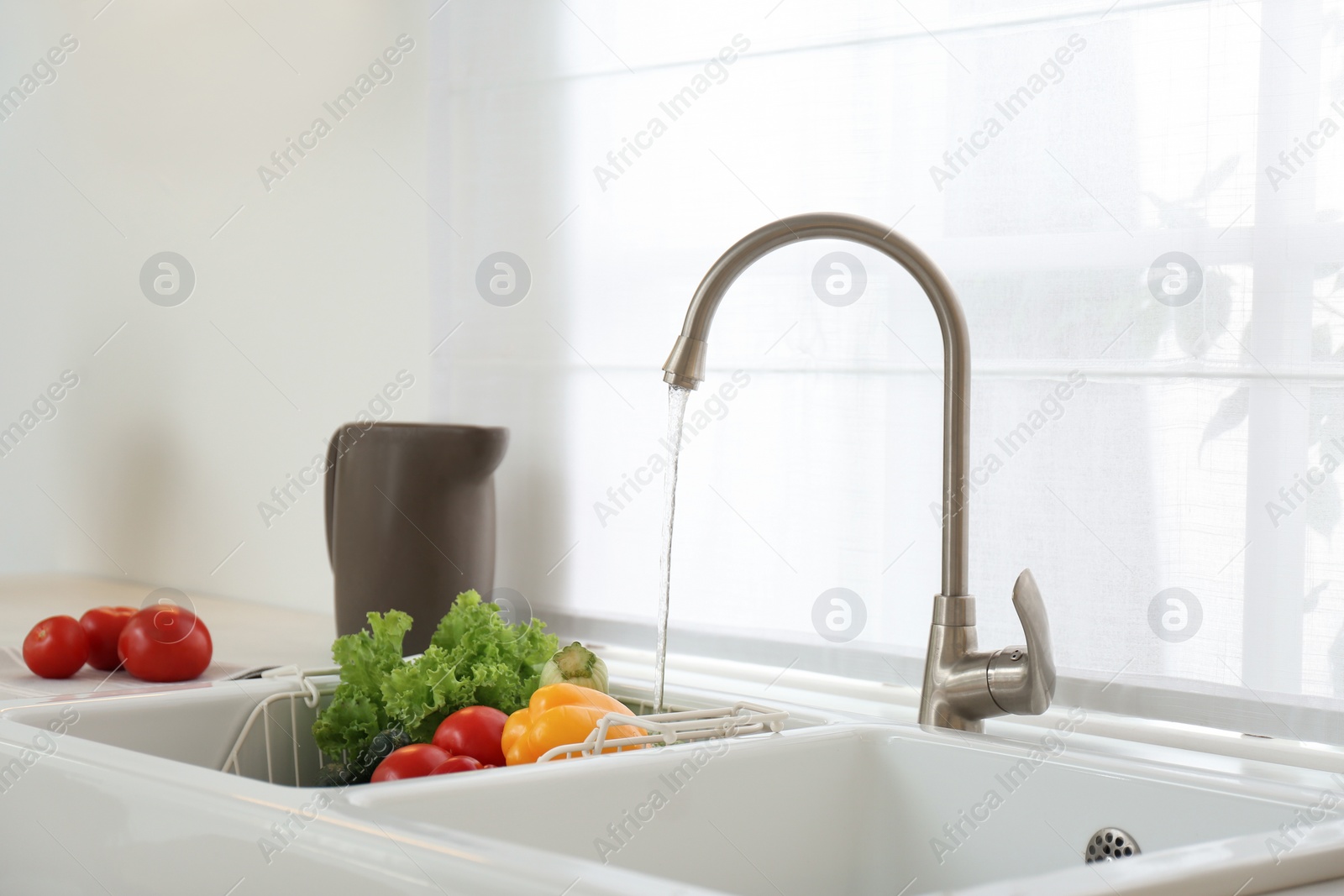 Photo of Many fresh ripe vegetables under tap water in kitchen sink