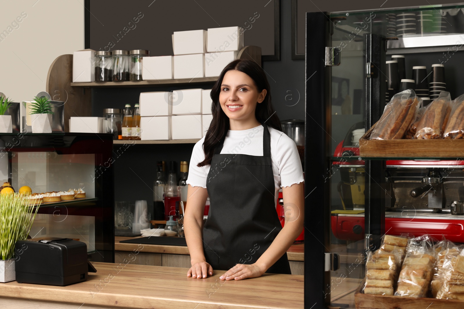 Photo of Business owner near showcases with pastries in her cafe