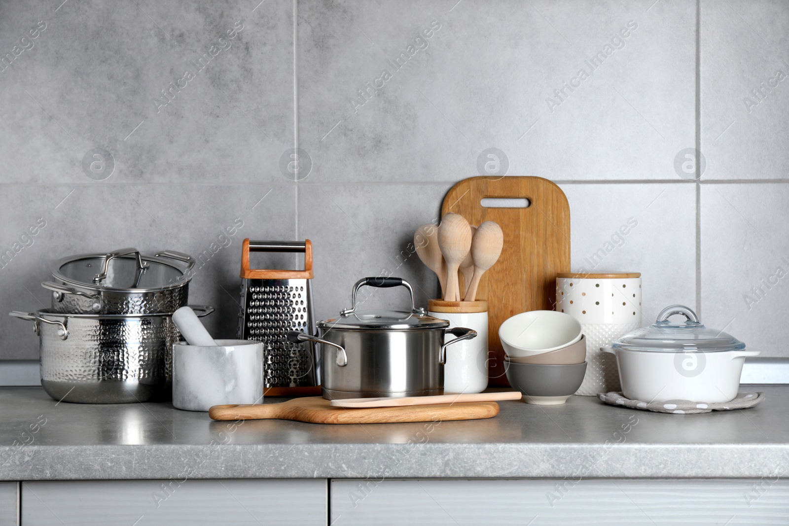 Photo of Set of different cooking utensils on grey countertop in kitchen