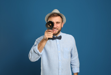 Young man using vintage video camera on blue background