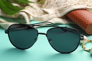 Photo of Stylish elegant sunglasses on turquoise background, closeup