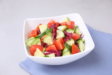 Photo of Bowl of vegetarian salad with cucumber, tomato, cabbage and onion on table