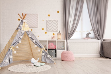 Photo of Cozy kids room interior with play tent and toys