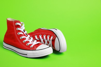 Photo of Pair of new stylish red sneakers on light green background. Space for text