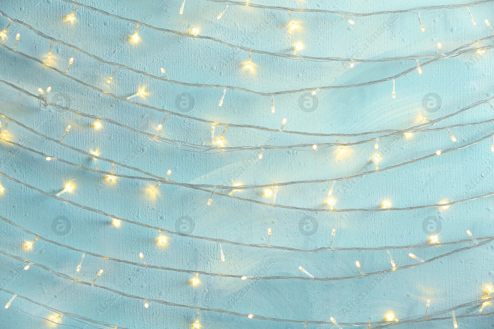 Photo of Christmas lights hanging on light blue stone wall