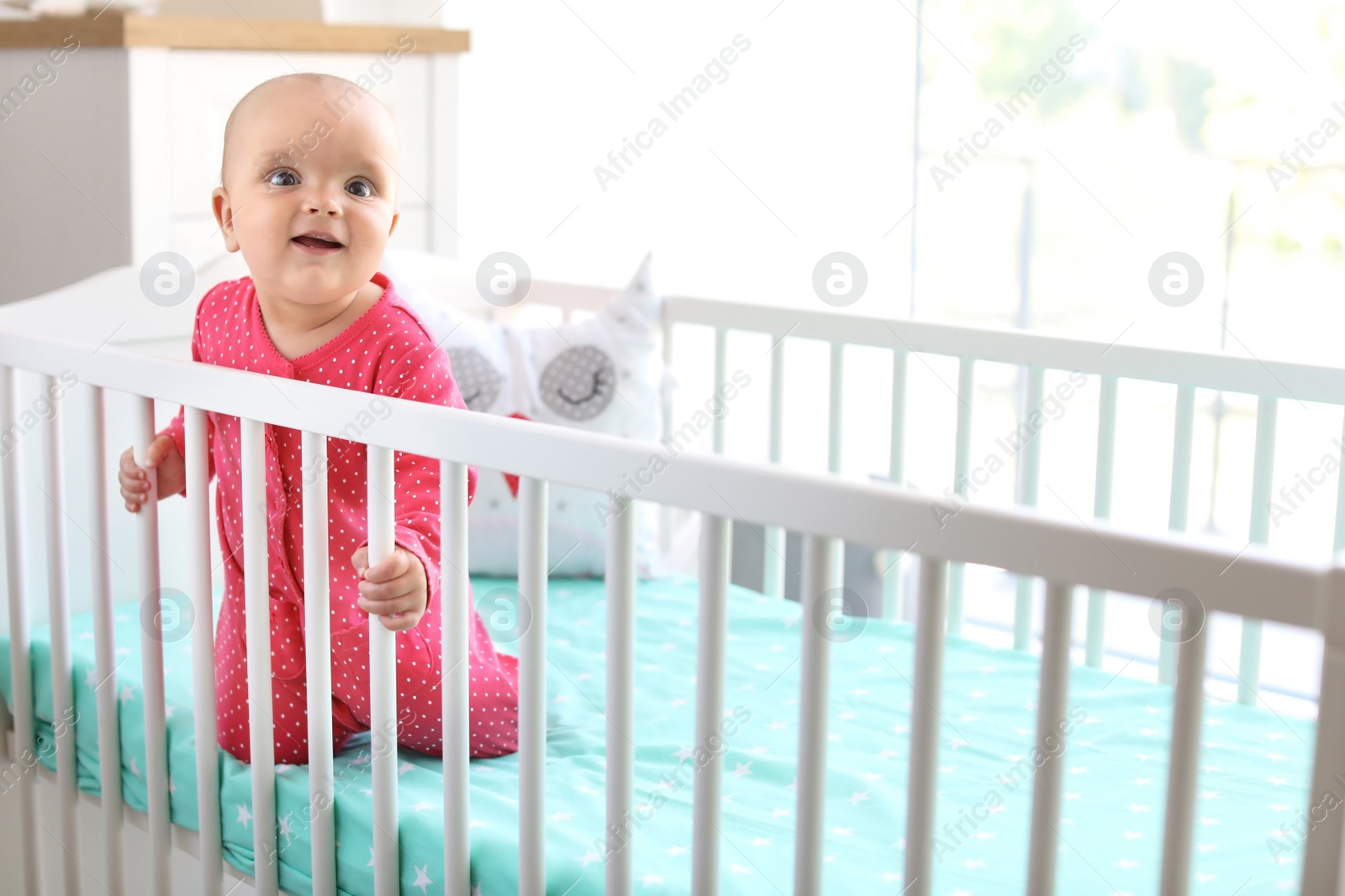 Photo of Cute baby girl in crib at home