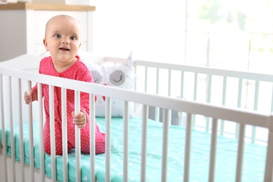 Cute baby girl in crib at home