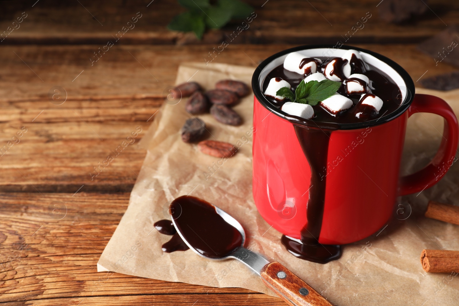 Photo of Mug of delicious hot chocolate with marshmallows and fresh mint on wooden table, closeup. Space for text