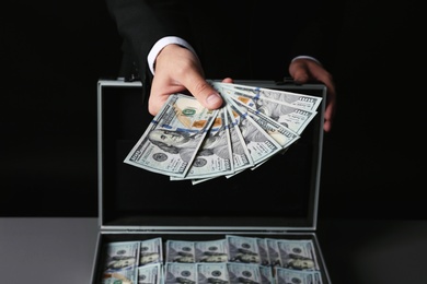 Businessman with suitcase offering money, closeup of hand