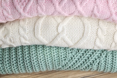 Image of Stack of folded warm sweaters on wooden table, closeup