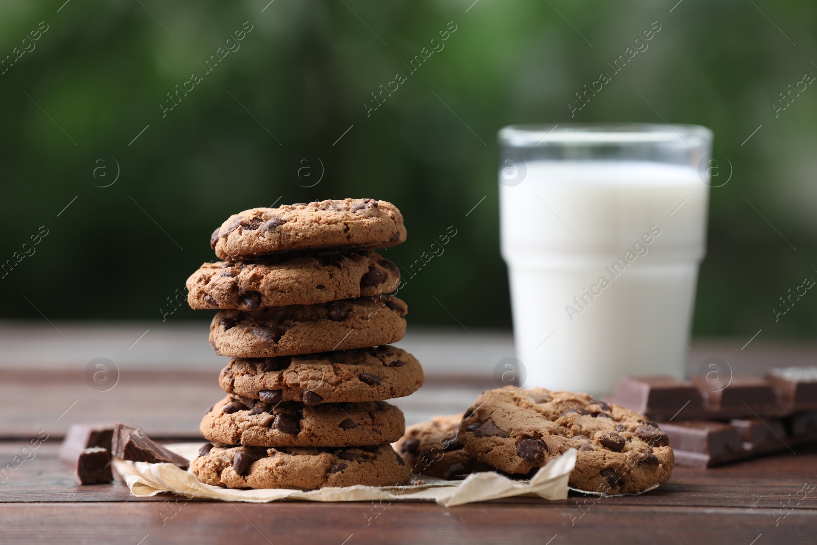 Photo of Delicious chocolate chip cookies and glass of milk on wooden table