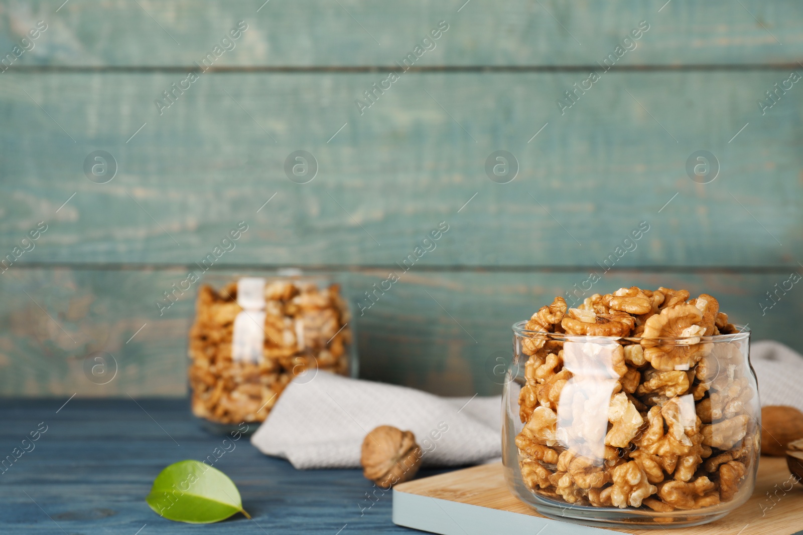 Photo of Dishware with walnuts on table against wooden wall. Space for text