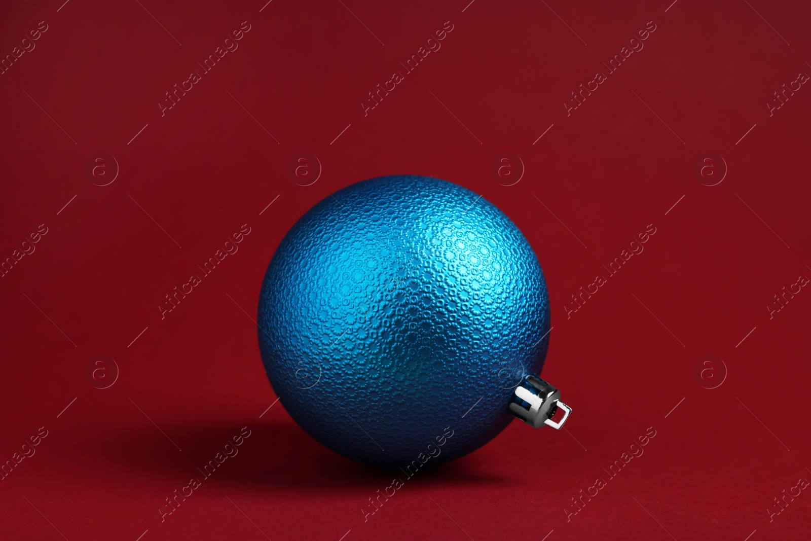 Photo of One blue Christmas ball on red background